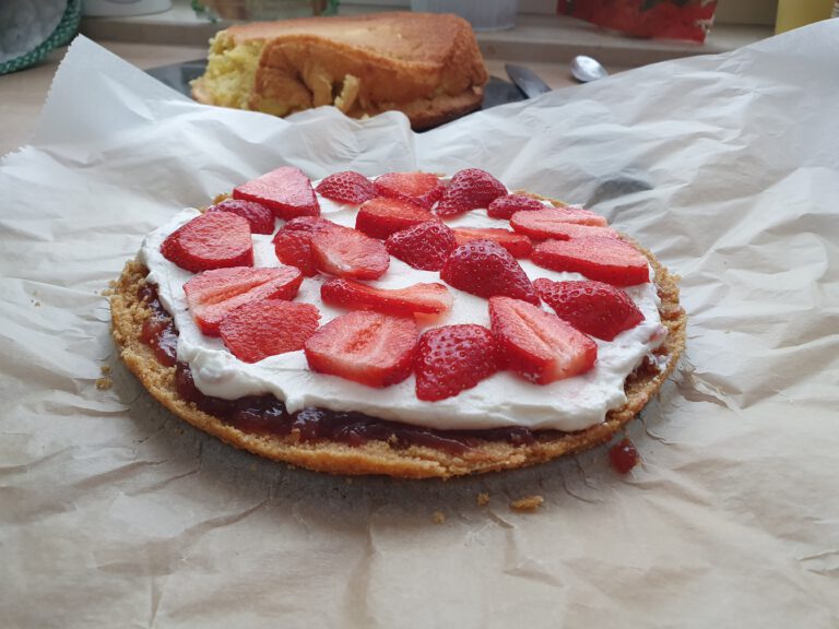 Ein Kuchen belegt mit weißer Creme und Erdbeeren.