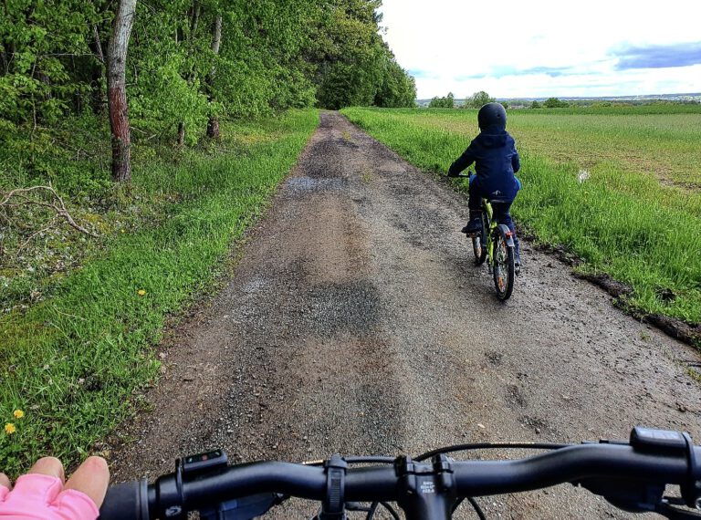 Ein Kind auf einem Fahrrad und das Lenkrad eines größeren Rades.