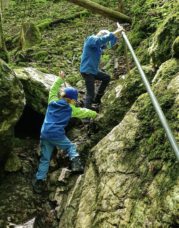 2 Kinder klettern zwischen Felsen.