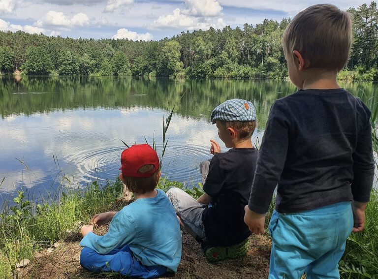 Drei Kinder an einem Weiher.