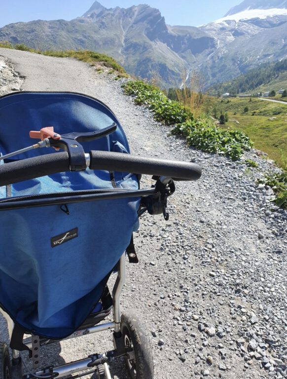 Ein blauer Kinderwagen in den Bergen.