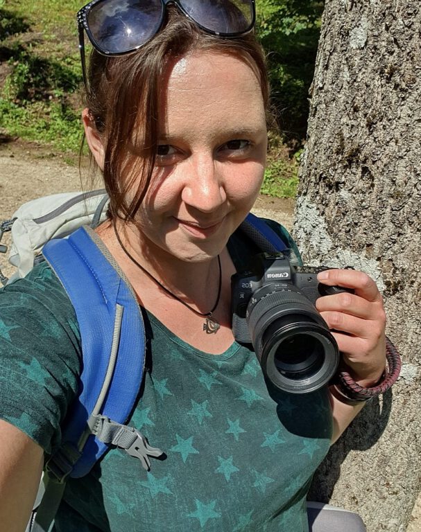 Ich trage ein grünes Shirt mit Sternen drauf, habe meine Canon in der Hand und mache ein Selfie von mir.