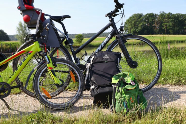 Ein großes und ein kleines Fahrrad an denen 2 Rucksäcke lehnen.