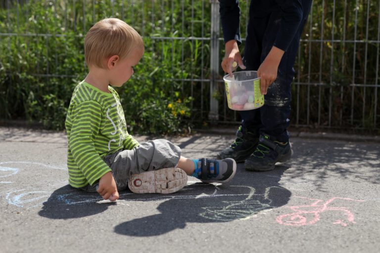 2 Kinder malen mit Kreide.