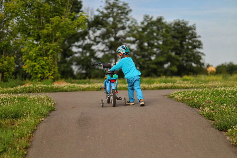 Ein Kind schiebt ein Fahrrad den Berg hinauf.