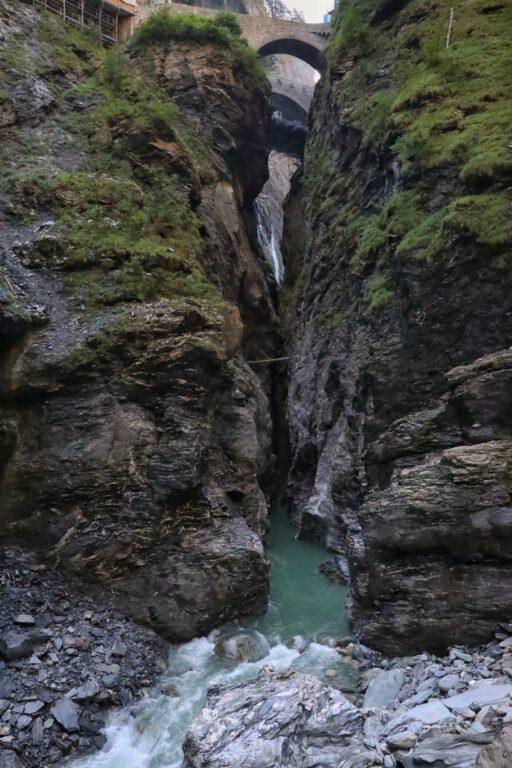 Eine Schlucht mit grauen Felsen und blau grünen Wasser.