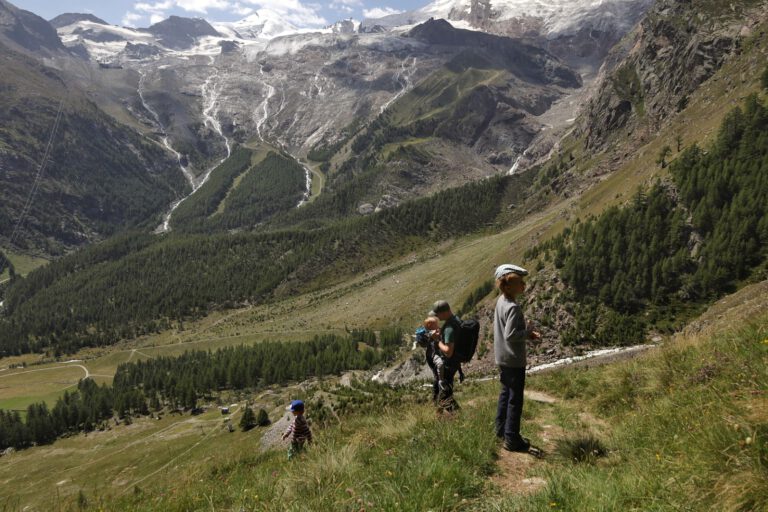 3 Personen stehen auf einen Berg und schauen sich andere Berge an