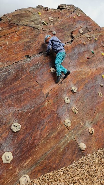 Eine Kletterwand mit einem Kind das nach oben klettert