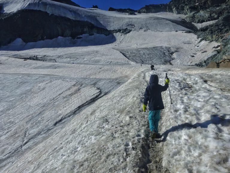 Ein Kind mit Wanderstock auf einem Berg im Schnee