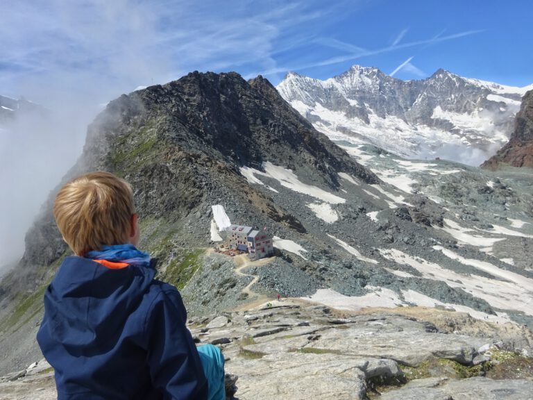 Links im Bild sitzt ein Kind. Es schaut auf die Berge