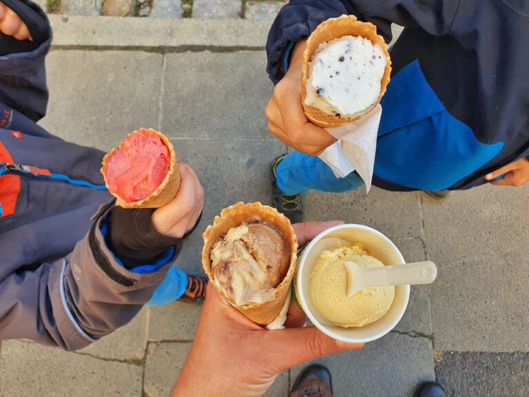 Vier verschiedene Kugeln Eis in der Waffel beziehungsweise im Becher.