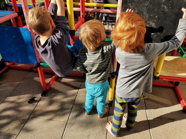 Drei Kinder die an einem Klettergerüst spielen.