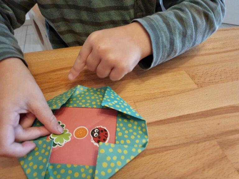 Eine kleine Kinderhand die Sticker auf Papier klebt.