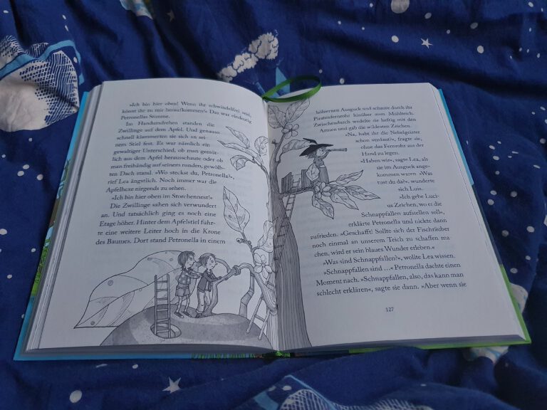 Ein aufgeklapptes Buch auf einer blauen Decke.