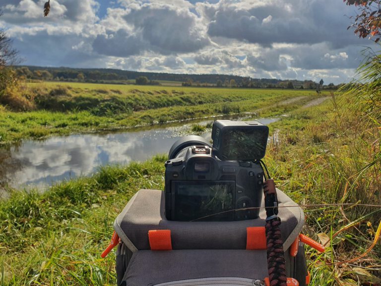 Eine Fotokamera auf einer Wiese auf der eine GoPro steht.