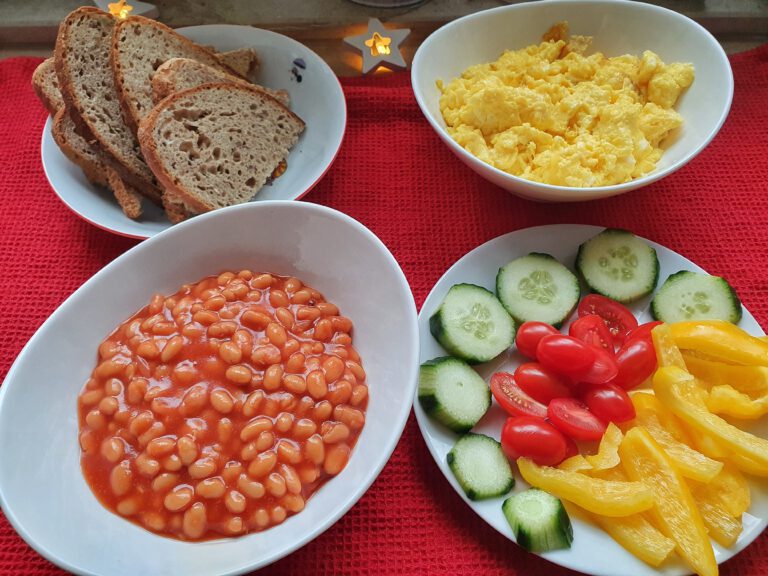 4 Schüsseln. Eine mit Brot, eine mit Rührei, eine mit gebackenen Bohnen und eine mit Gurke, Tomaten und Paprika. 