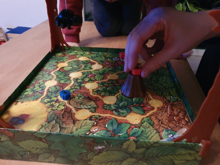 Hände eines Erwachsenen der Spielfiguren über ein Spiel Spielbrett zieht.