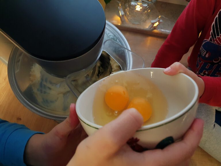 Zwei aufgeschlagene Eier die in eine Maschine geschüttet werden.