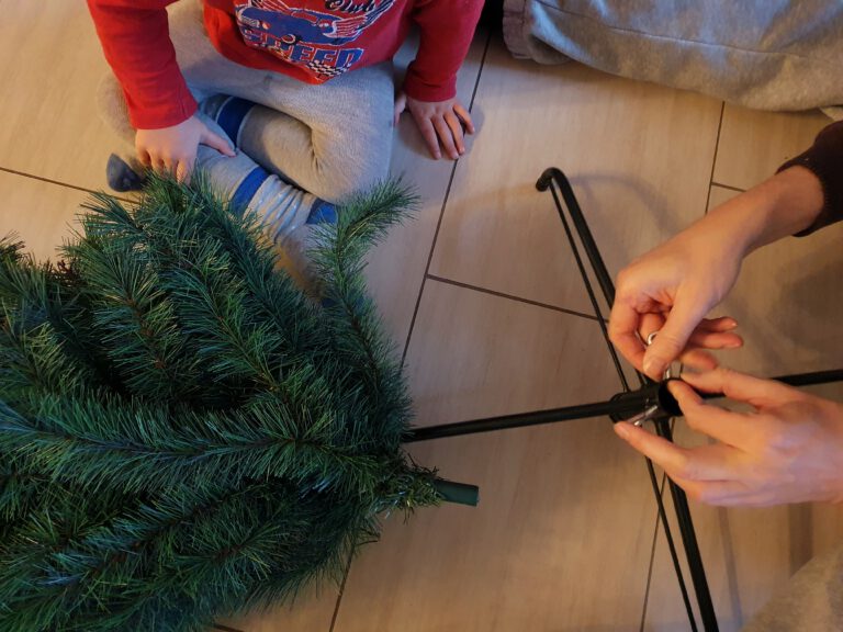 Ein Erwachsener und ein Kind, die einen Weihnachtsbaum aufstellen.