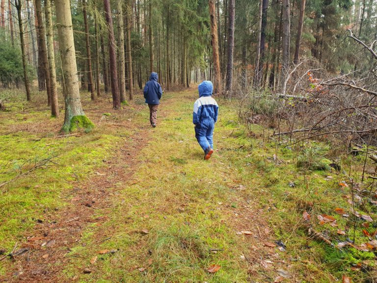 2 Kinder laufen durch einen Wald.