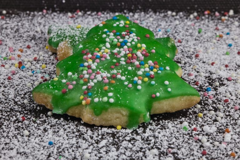 Ein grünes Tannenbaumplätzchen mit bunten Streusel.