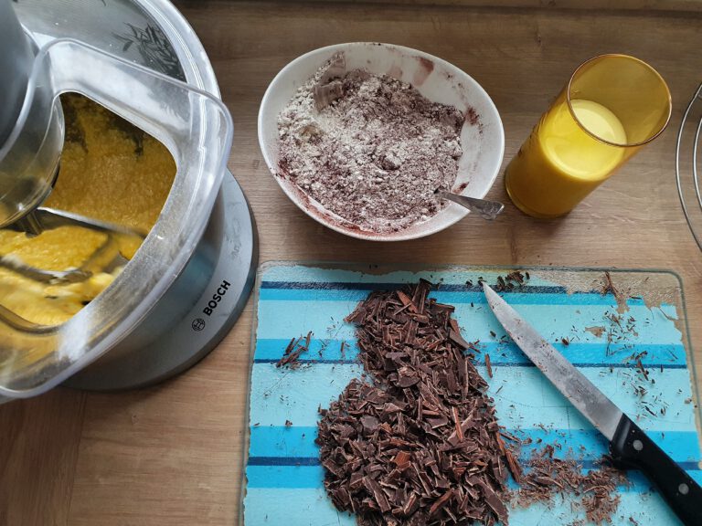 Eine Küchenmaschine die rührt. Gehackte Schokolade. Ein Glas Milch und eine Schüssel Mehl.