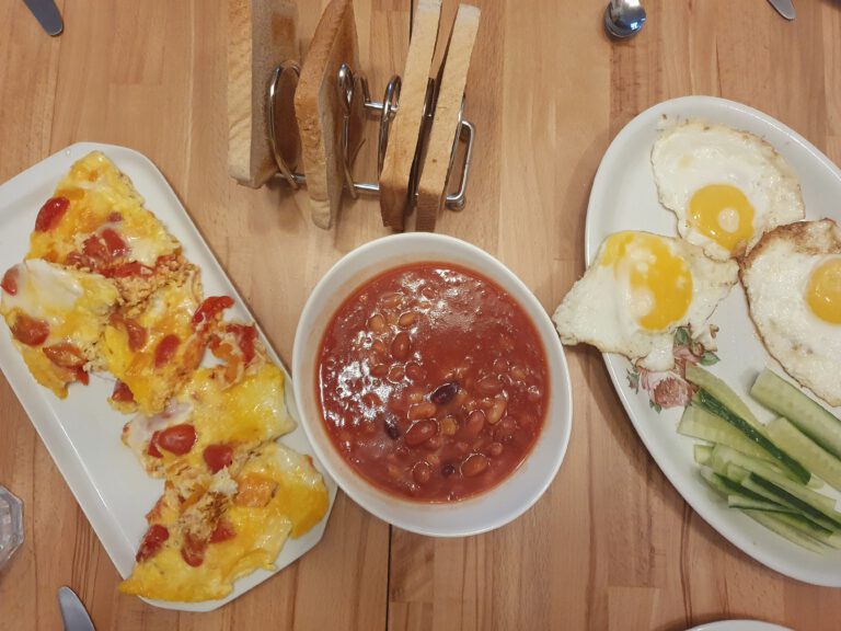 Omelette, Bakes Beans, Spiegelei, Gurken und Toast.