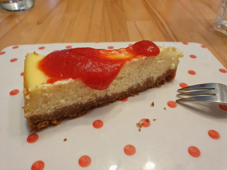 Ein Stück New York Cheesecake mit Erdbeerpüree.