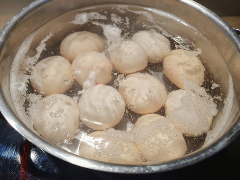 Einige Eier die einem Topf kochen.