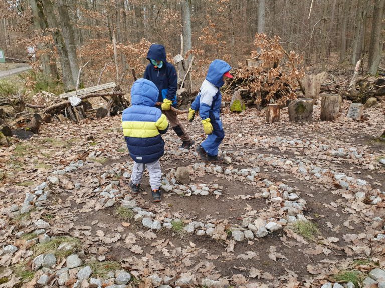 3 Kinder die in einem Steinkreis spielen.