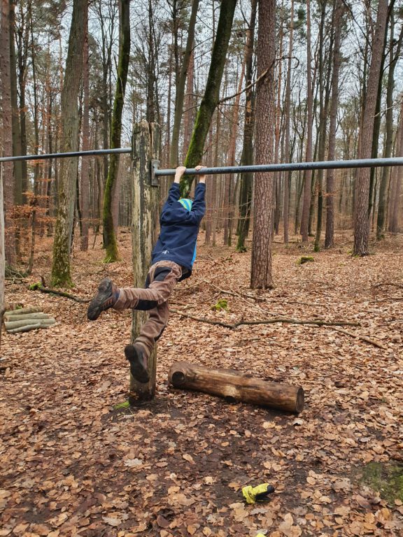 Ein Kind hängt an einer Stange und schaukelt.