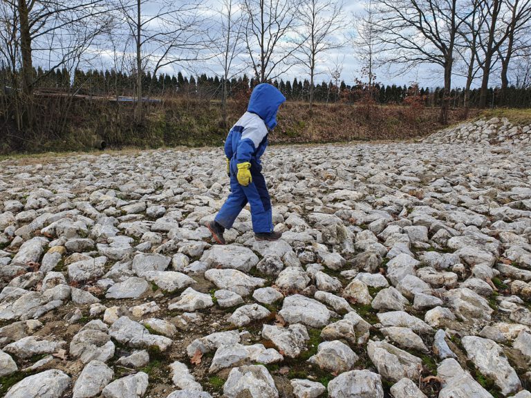 Ein Kind läuft über große Steine.