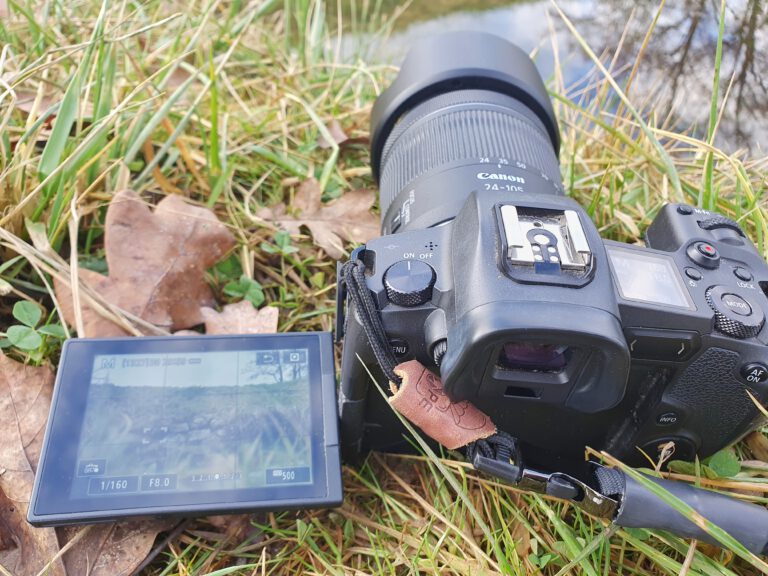 Eine schwarze Kamera die im Gras liegt.