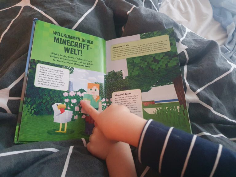 Ein Buch über Minecraft welches von kleinen Händen gehalten wird.