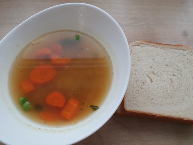 Ein Teller Suppe und Weißbrot.
