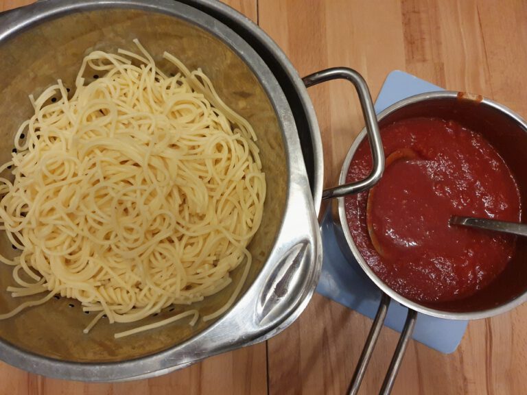 Ein Topf mit Spaghetti und ein Topf mit Tomatensoße.