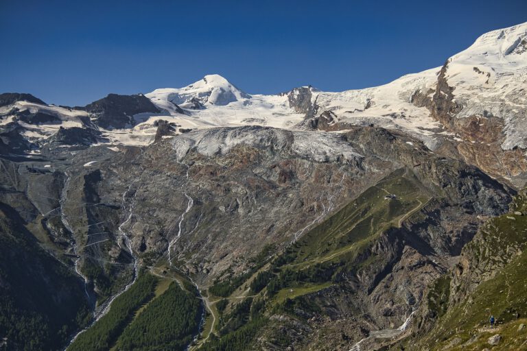 Hohe Berge die schneebedeckte Gipfel haben. Weiter unten wird es grüner.