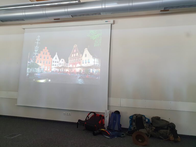 Auf einer Leinwand ist ein Bild zu sehen welches im dunkeln in einer Stadt aufgenommen wurde.