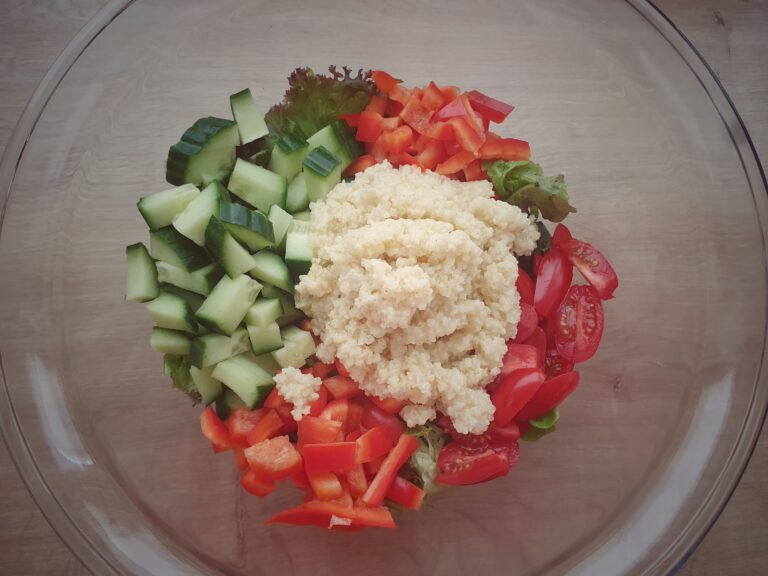 Eine Schüssel mit Salat, Paprika, gurke, Tomaten und Hirse.