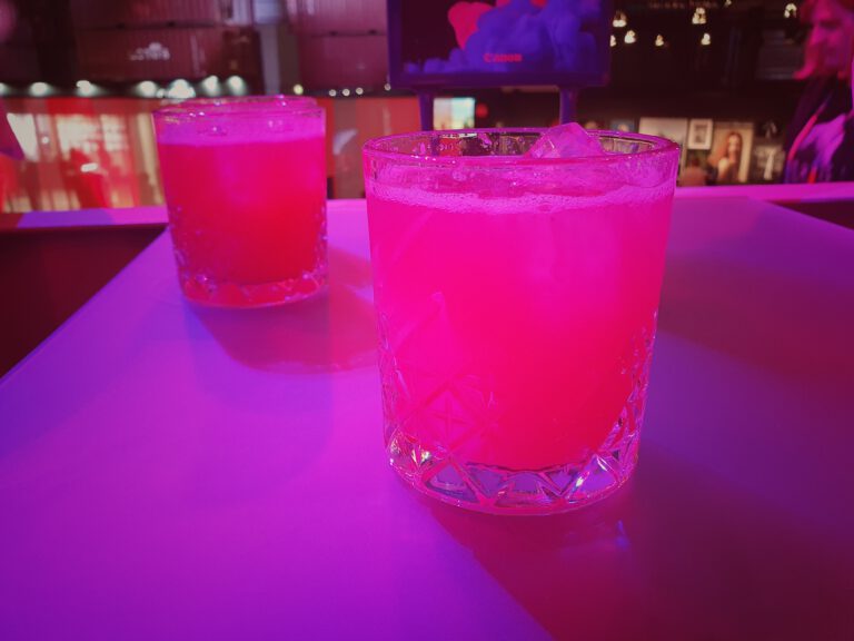 Mehrere Cocktailgläser auf einem Tisch. Das Licht ist rötlich-pink.