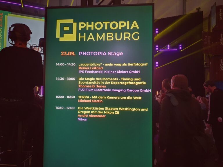 Eine Digitalanzeige mit "Photopia Hamburg" die anzeigt welche Speaker wann und wo auftreten.