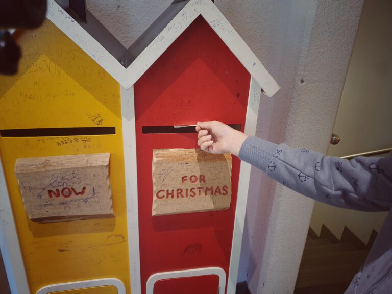Zwei Briefkästen. Auf dem gelben steht "now" - auf dem roten steht "for christmas"